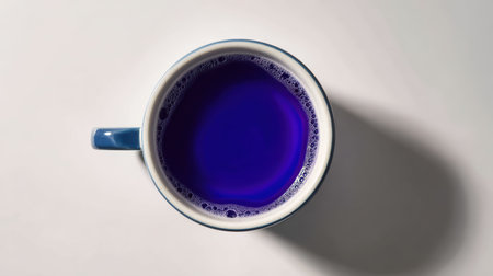 This image features a blue ceramic cup filled with a vibrant purple liquid on a light surface. The aerial perspective highlights its simplicity and modern design.の素材