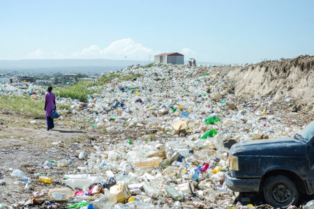 A stark visual representation of environmental pollution as a solitary figure stands amidst an overwhelming amount of plastic waste against a bright sky.の素材
