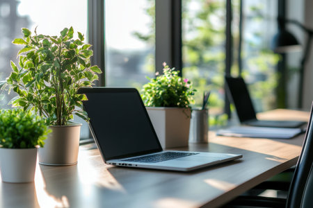 A stylish modern workspace featuring a sleek laptop, vibrant green plants, and ample natural light, ideal for creativity and productivity.の素材