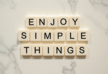 A captivating arrangement of white tiles displaying the words "Enjoy Simple Things" on a smooth marble background, representing positivity and inspiration.の素材
