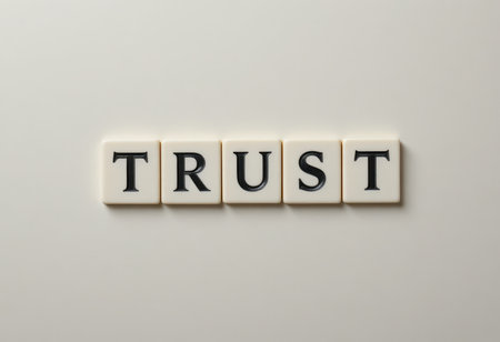 A close-up image featuring letter tiles spelling the word "TRUST" against a soft background, symbolizing the importance of trust in relationships and communication.の素材
