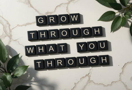 A serene arrangement featuring a motivational quote on a marble background, surrounded by fresh leaves, symbolizing growth and resilience in life's journey.の素材