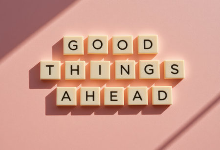 A vibrant arrangement of letter tiles spelling "Good Things Ahead" on a soft pink background, radiating positivity and encouragement for a bright future.の素材