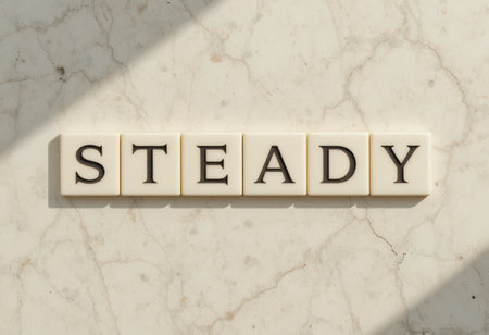 A close-up view of letter tiles arranged to spell "steady" on a light stone surface. This minimalist design highlights simplicity and elegance, ideal for creative projects.の素材