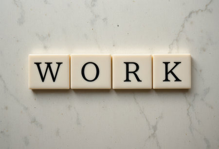 Elegant arrangement of letter tiles spelling "WORK" on a marble surface. Ideal for themes of motivation, productivity, and professionalism in office settings.の素材