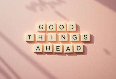 This image features letter tiles arranged to spell "Good Things Ahead" against a soft pink background, casting gentle shadows and evoking a sense of positivity and inspiration.の素材