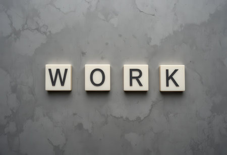A minimalistic image of white tiles spelling the word "WORK" against a textured gray marble surface. Perfect for conveying themes of productivity and motivation in the workplace.の素材
