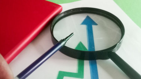 Magnifying glass with red book and green arrow on white background.の写真素材