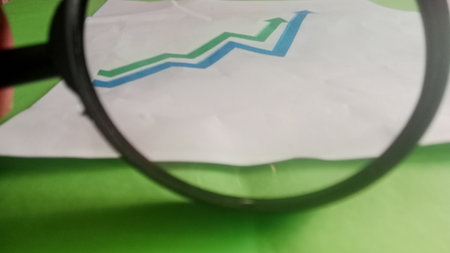 Magnifying glass on a green sheet of paper with a graph.の写真素材