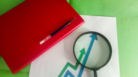 Magnifying glass and red notebook on green background. Top view.の写真素材
