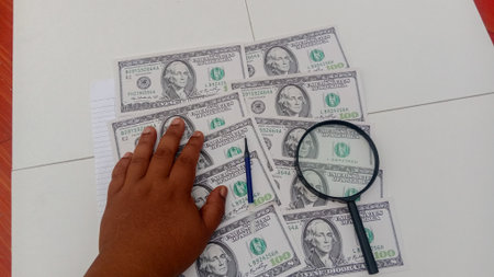 Close-up of a child's hand counting money with a magnifying glass