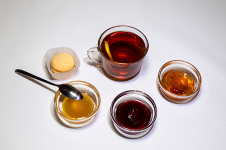 A cup of strong tea, rosettes with raspberry jam, apples and honey. White background.の写真素材
