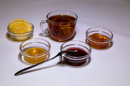 A cup of strong tea, rosettes with raspberry jam, apples and honey. White background.の写真素材