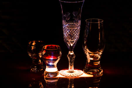 The play of light. A set of wine glasses and glasses for strong drinks on the illuminated bar...