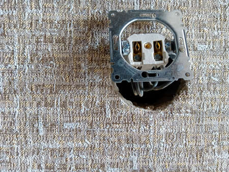 An electrical outlet without a cover sticks out of the wall.の写真素材