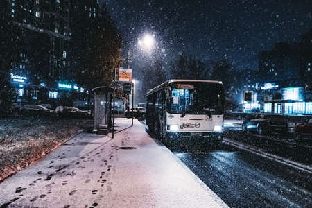 Bus at the stop under the snow at night at the lampの写真素材