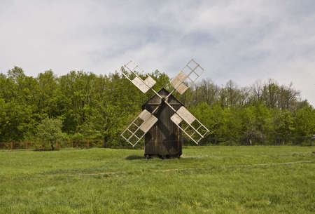 Landscape with wooden windmill on meadow  Recorded in outdoors museum of wooden architecture in Pirogovo, near Kiev, capital of Ukraine の写真素材