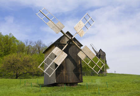 Wooden windmill on green field, recorded in outdoors museum of national architecture in Pirogovo, near Kiev, capital of Ukraine.のeditorial素材