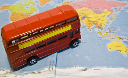 Red toy touristic bus standing on map of the world.の写真素材