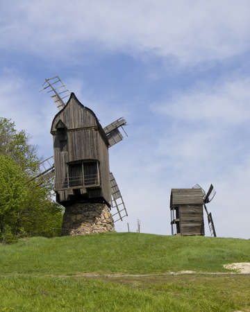 Pirogovo, Ukraine - May 05, 2010: Few real old wooden windmills on green field, recorded in outdoors museum of national architecture in Pirogovo near Kiev, capital of Ukraine.のeditorial素材