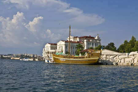 Ukraine, Crimea, Sevastopol - July 20, 2010: sailing retro ship and buildings on quay in harbour.のeditorial素材
