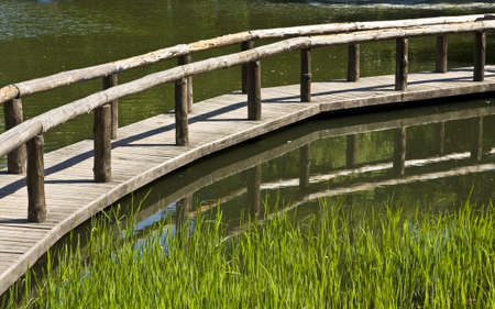Summer landscape - wooden bridge on water with reflection and grass.の写真素材