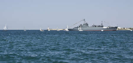 Sevastopol, Ukraine - July 22, 2010: Big military ship and many little white sailing boats around in sea. Recorded in town Sevastopol in Crimea on Black sea.のeditorial素材