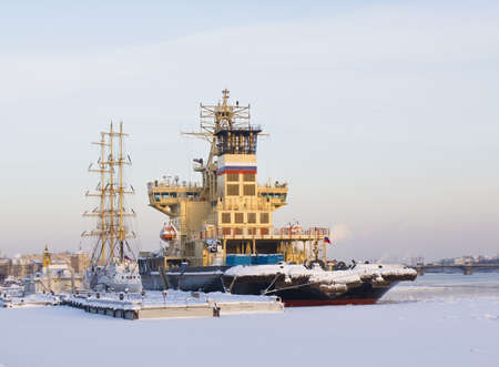 Modern and sailing ships on river neva in winter in snow and ice, in town St. Petersburg, Russia.のeditorial素材