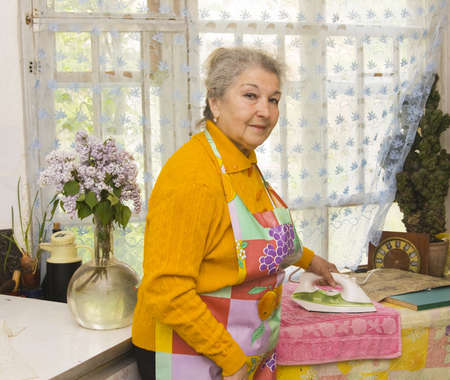 Old lady European ironing in the house.の写真素材