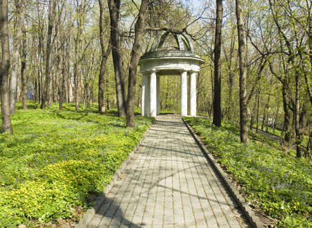 Spring landscape with summerhouse  pavilion  in park with trees and primroses around の写真素材