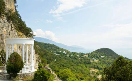 Sea landscape with white colonnade on shore and rocks, recorded in place Oleandra in region Crimea...