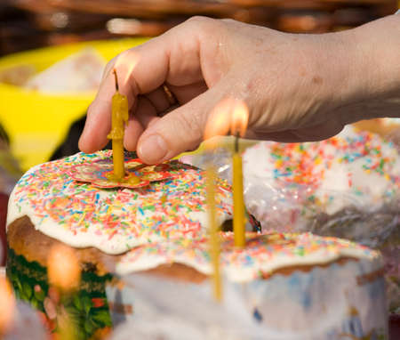 Hand lightes up candle on Easter cake.の写真素材
