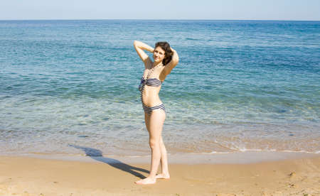 Young Euiropean woman with brown hair in bikini on sea beach.の写真素材