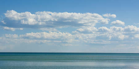 Seascape with calm blue sea and big clouds on sky, sunny day.の写真素材