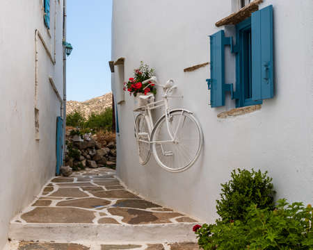 Street scene on the island of Tinos, Greece. The white-washed buildings are typical in this region of the country. Decorative bicycle on the wall.の写真素材