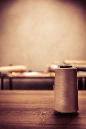 Thread spool with sewing tools at table. Concept of clothes atelier workplace