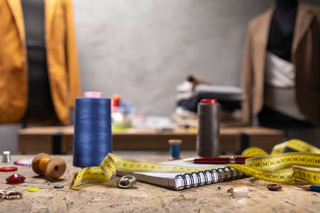 Sewing tools and tailor suit jacket on tailor mannequin. Concept of clothes atelier workplaceの写真素材