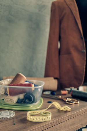 Sewing tools and tailor suit jacket on tailor mannequin. Concept of clothes atelier workplaceの写真素材