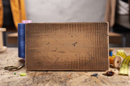 Wooden nameplate and sewing tools at wood table. Concept of clothes atelier workplaceの写真素材