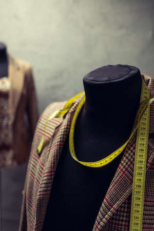 Suit jacket on tailor mannequin and tape measure. Concept of clothes atelier workplaceの写真素材