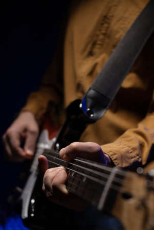 Man holding electric guitar. Musician in studio with electric guitar near wall