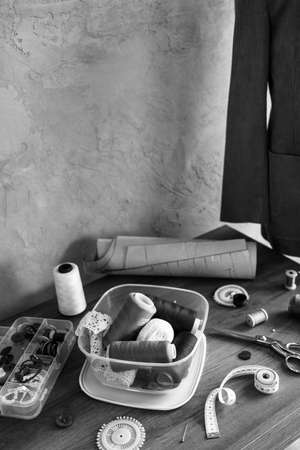 Sewing tools and tailor suit jacket on tailor mannequin. Concept of clothes atelier workplaceの写真素材