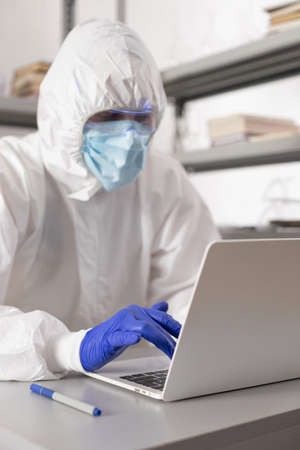 Scientist working computer laptop looking at test tube with liquid reagent. Lab scientist and...