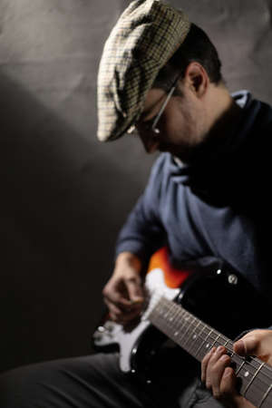 Man playing electric guitar. Musician in studio with electric guitar near wall