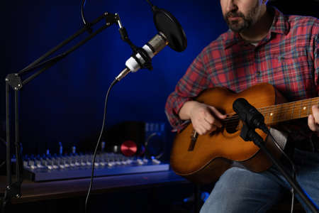 Man singing and playing guitar. Musician singer in record studio holding acoustic guitar