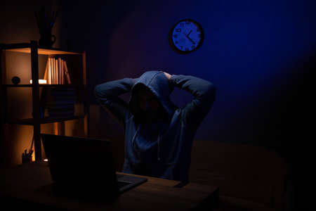 Hacker man thinking laptop computer. Hacker attack in dark room background