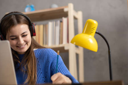 Girl speaking in headphones and writing at notebook. Student woman online larning. Creative...