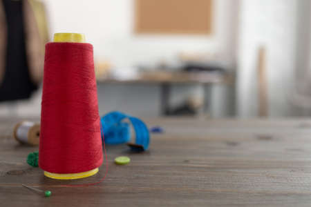 Spool of thread and tailor or sewing accessories with tools at table. Concept of clothes atelier workplaceの写真素材