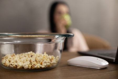 Girl looking laptop computer drinking and eat popcornの写真素材