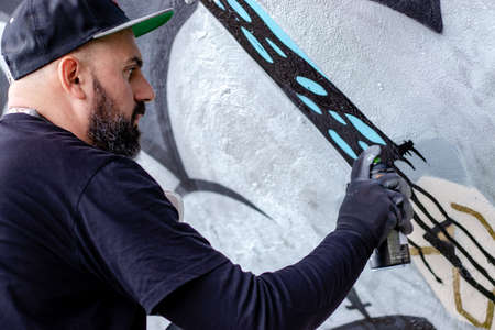 Graffiti artist in action, drawing on the wall with aerosol spray paint in a can. Street art culture concept.の写真素材
